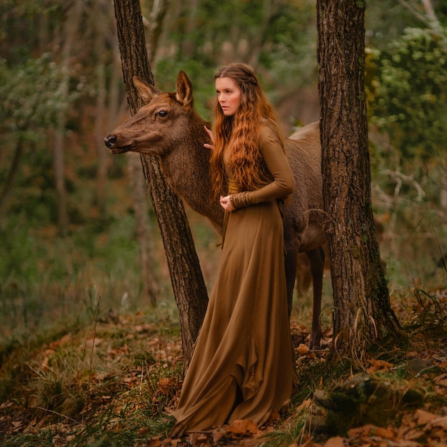 Fille rousse avec un cerf dans une robe longue