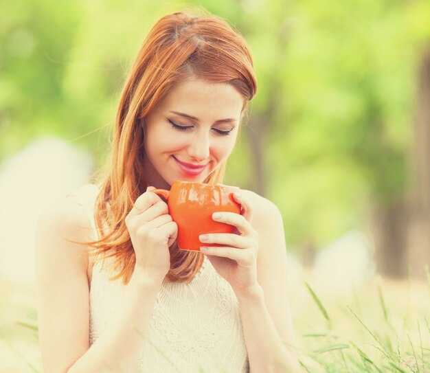 Fille rousse avec une coupe orange en plein air