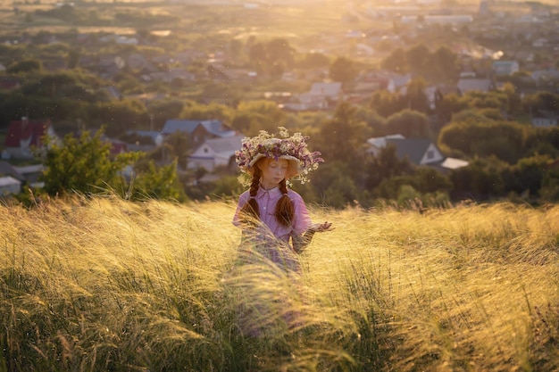 Fille rousse dans un chapeau au coucher du soleil sur un pré