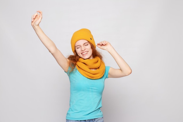 Fille rousse dans un chapeau chaud sur fond clair