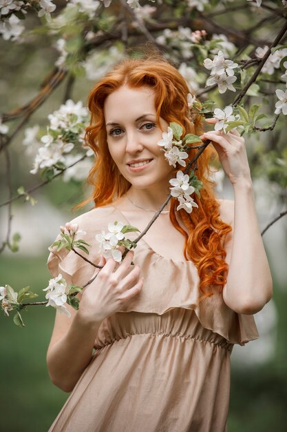 Fille rousse dans une robe beige dans le jardin