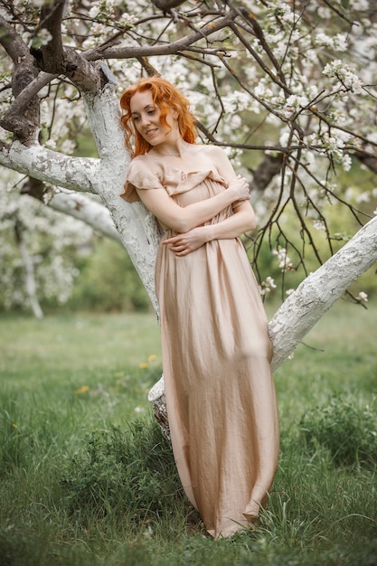Fille rousse dans une robe beige dans le jardin