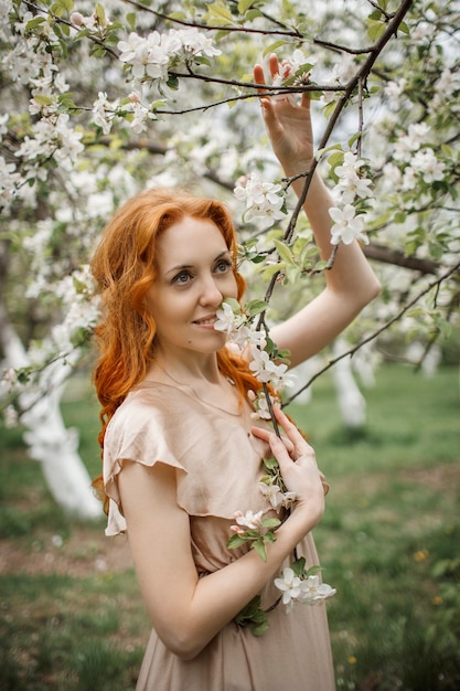 Fille rousse dans une robe beige dans le jardin