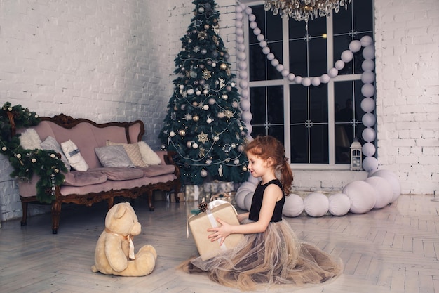 La fille rousse donne le cadeau de Noël à l'ours de nounours