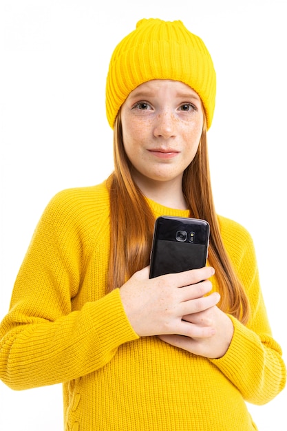 Fille rousse européenne avec un téléphone dans ses mains