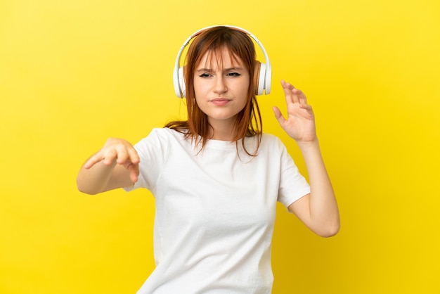 Fille rousse isolée sur fond jaune, écouter de la musique et danser