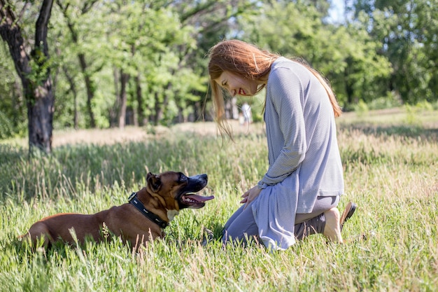 Fille rousse joue avec un chien dans le parc