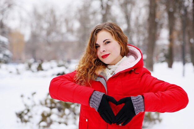 Fille rousse montrant un cœur avec ses mains le jour de la Saint-Valentin