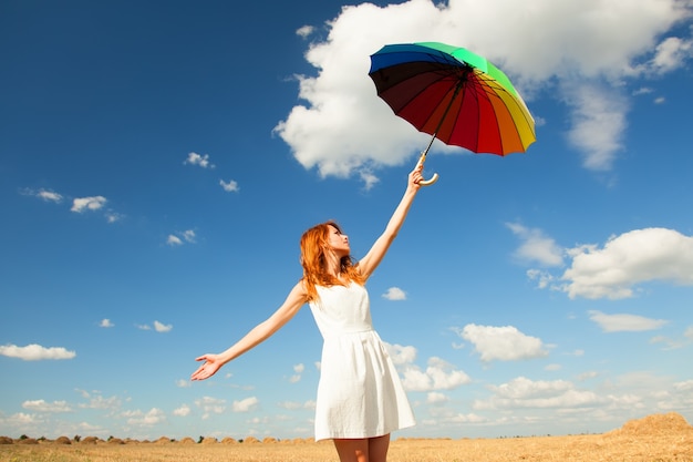 Fille rousse avec parapluie au champ