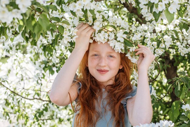 Fille rousse parmi les branches d'un pommier dans le jardin