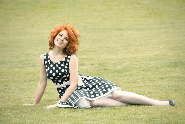 Fille rousse souriante assise sur l'herbe et souriant