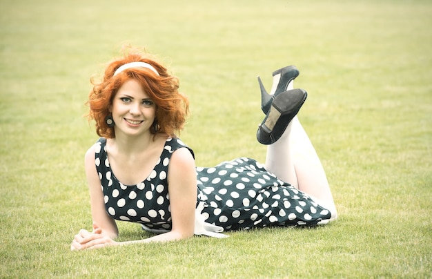 Fille rousse souriante assise sur l'herbe et souriant