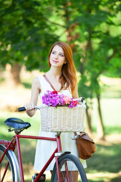 Fille rousse avec vélo rétro dans le parc.