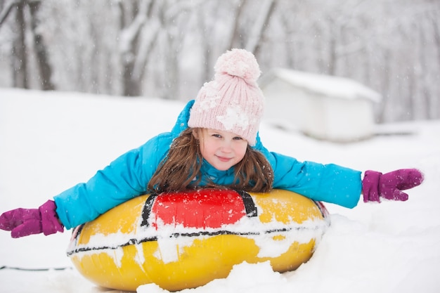 Fille s'amusant sur la neige tube. Fille monte un tube.