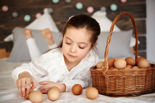 Fille s'amusant avec des œufs au lit