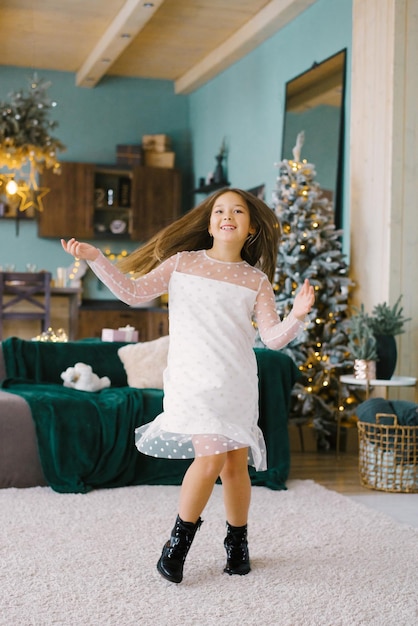 Une fille s'amuse et danse dans un élégant salon de style scandinave décoré pour Noël