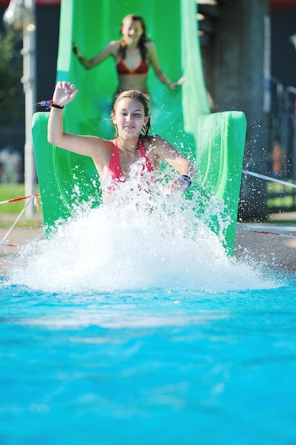 La fille s'amuse sur le toboggan à l'extérieur de la piscine.