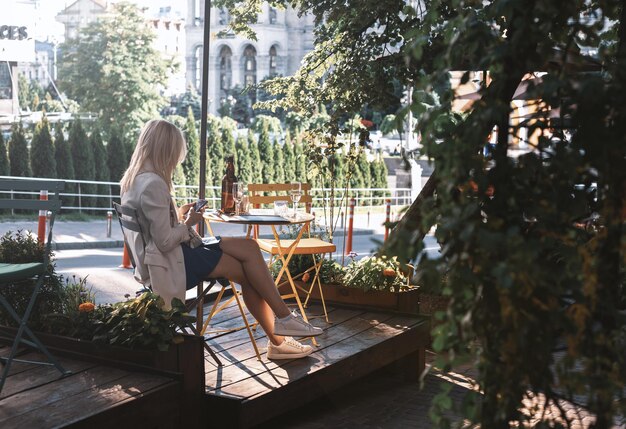 La fille s'assied dans un café sur une terrasse d'été