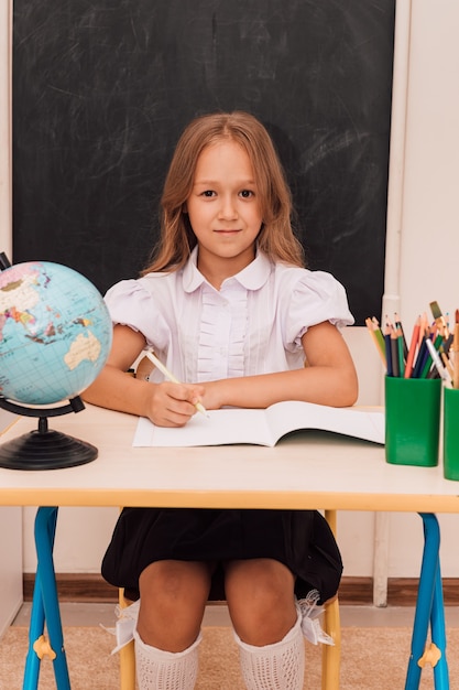 La fille s'assied à la leçon au bureau