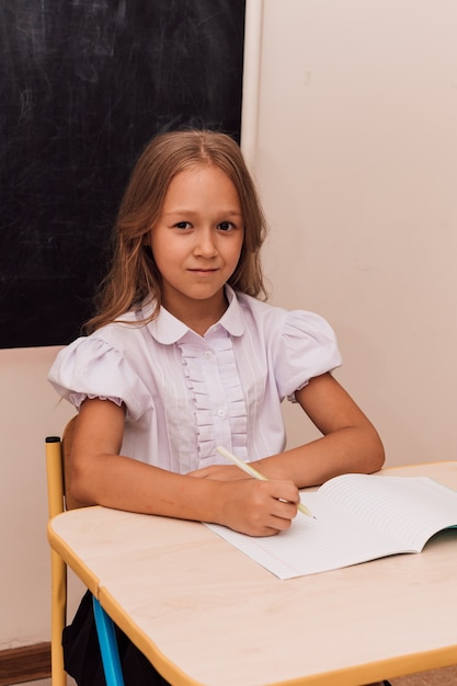 La fille s'assied à la leçon au bureau