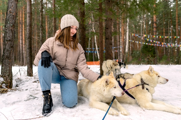 La fille s'assoit à côté d'un husky sibérien blanc et la caresse.