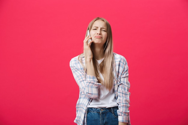 Fille s&#39;ennuie appeler au téléphone et avoir l&#39;air fou sur un fond rose