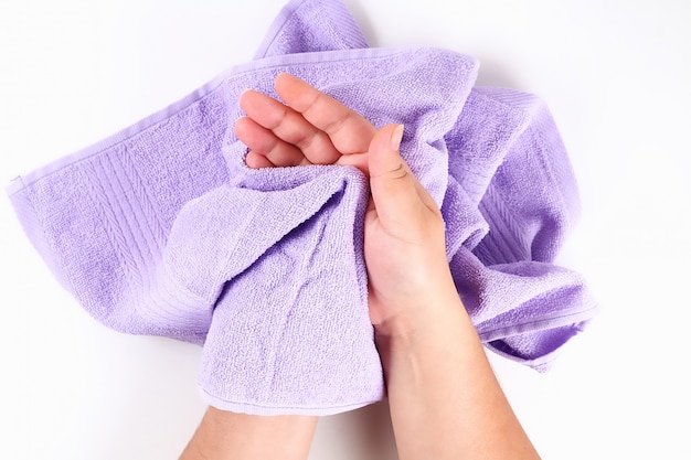 Fille s&#39;essuie les mains avec une serviette violette sur blanc. Vue de dessus.