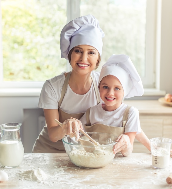 Fille et sa belle maman en tabliers et cuisine des chapeaux.