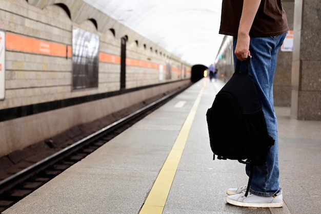 Une fille avec un sac à dos attend un train à la gare