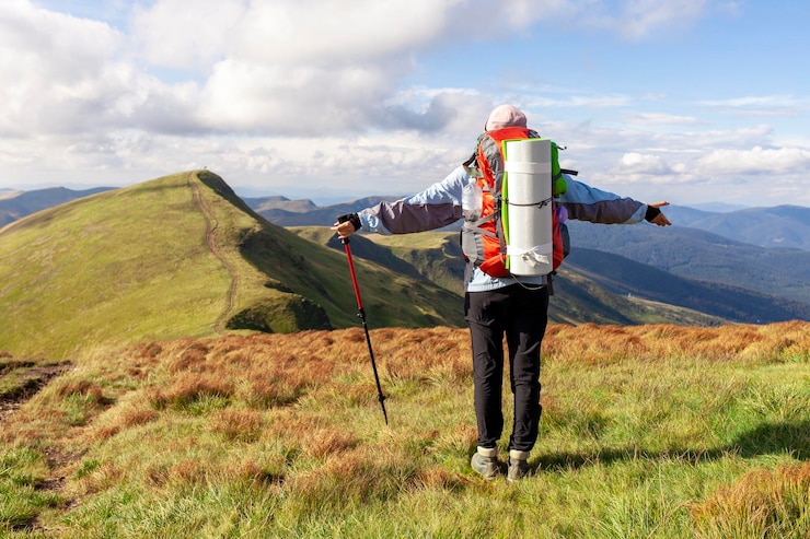 Photo fille avec sac à dos et équipement de randonnée se dresse et regarde le sommet de la touriste de montagne