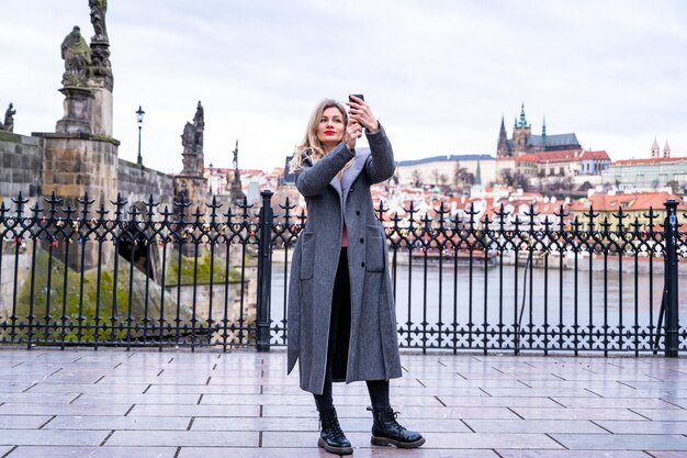 Une fille avec un sac à dos fait une photo au téléphone du pont Charles de Prague. fille touristique