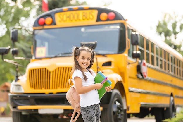 Fille avec sac à dos près du bus scolaire jaune. Transport pour les étudiants