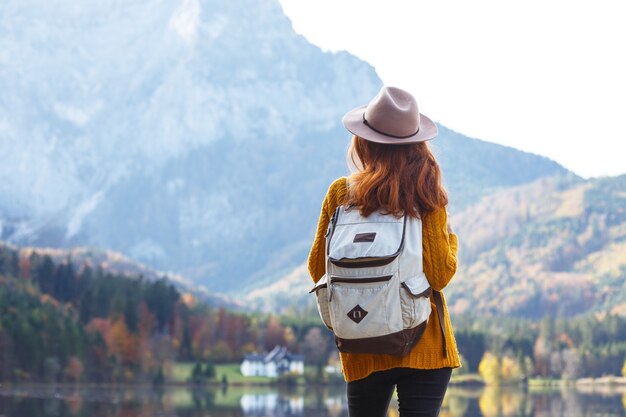 Fille avec un sac à dos se dresse sur la rive d'un lac de montagne