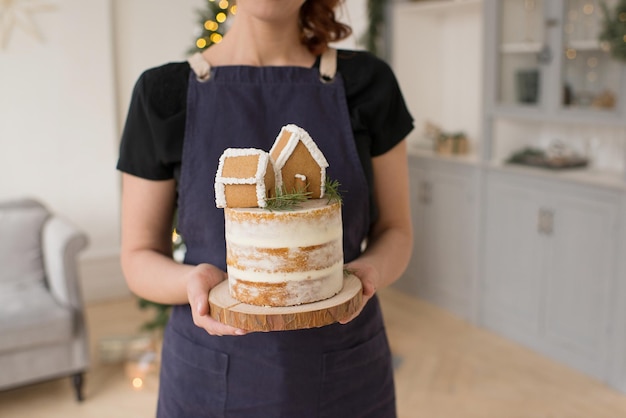 Une fille sans visage tient un gâteau de Noël avec des maisons dans ses mains