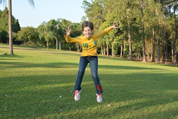 Une fille sautant sur l'herbe dans le parc.