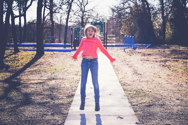 Photo une fille sautant sur une passerelle dans un parc.