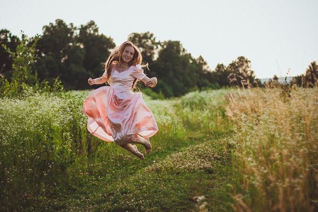 Fille sautant sur le terrain dans une robe rose