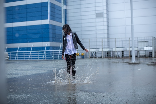 La fille saute sur une énorme flaque d'eau.