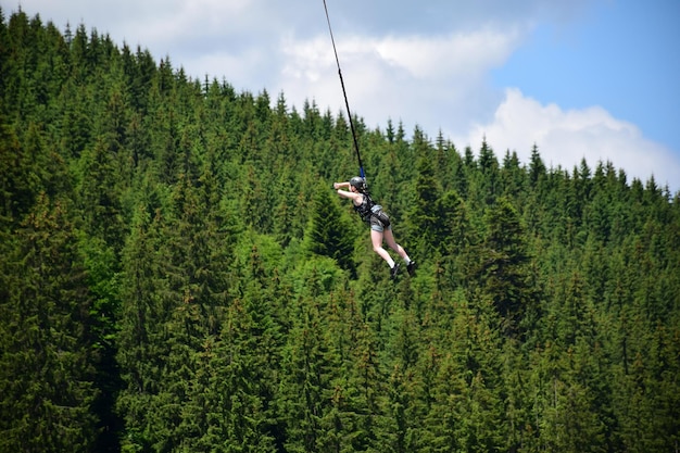 Une fille a sauté d'un saut à l'élastique suspendu à une corde raide à haute altitude