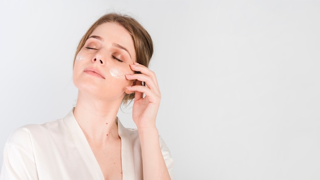 Fille se appliquant un produit cosmétique