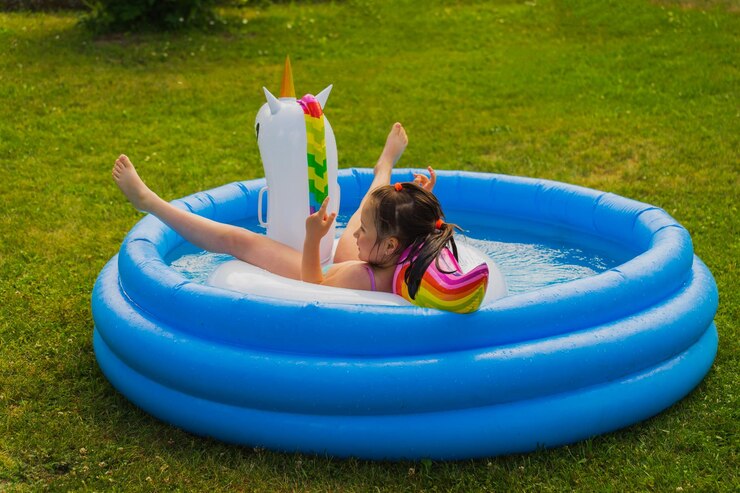 Photo une fille se baigne avec une licorne en caoutchouc dans une piscine gonflable dans la nature par une chaude journée d'été