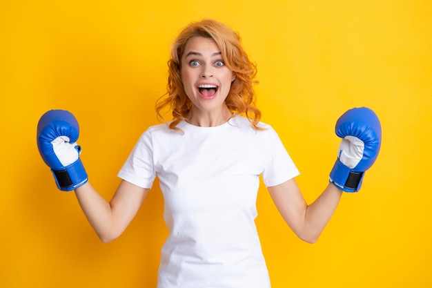 Fille se battre pour le succès boxeuse gagnante avec ses mains levées excité isolé sur jaune