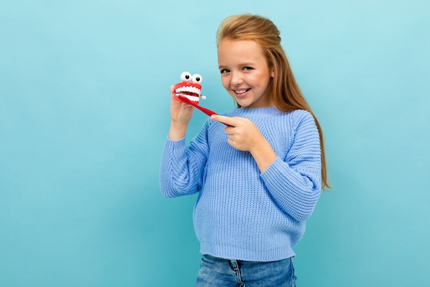 Fille se brosse les dents sur un fond bleu studio.