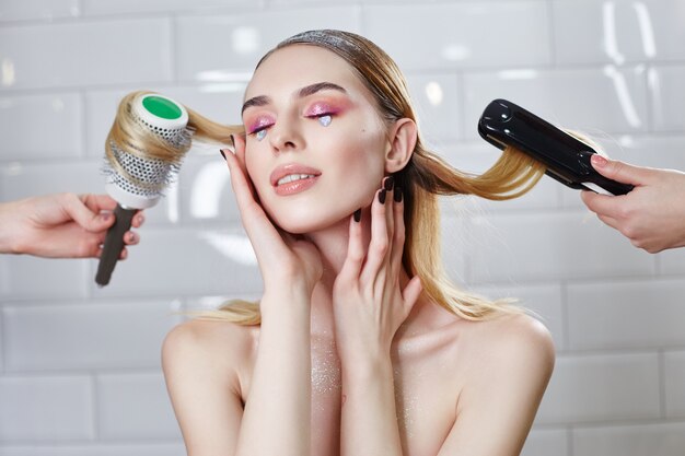 La fille se coiffe dans un salon de beauté, se coiffe et se peigne. Femme avec un maquillage créatif brillant et brillant dans un salon de beauté, soins capillaires