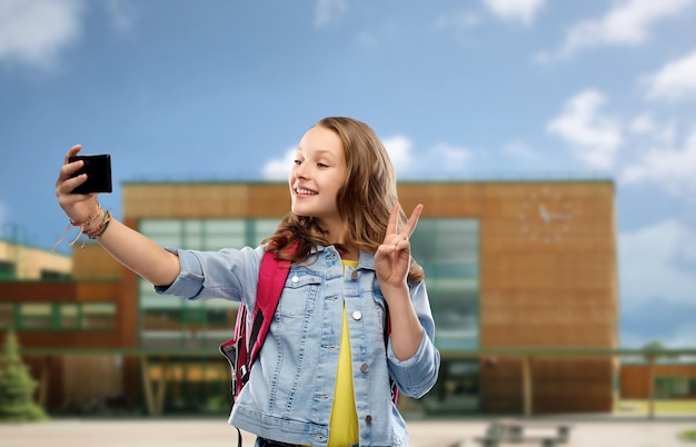 Une fille se fait un selfie avec son smartphone à l'école.