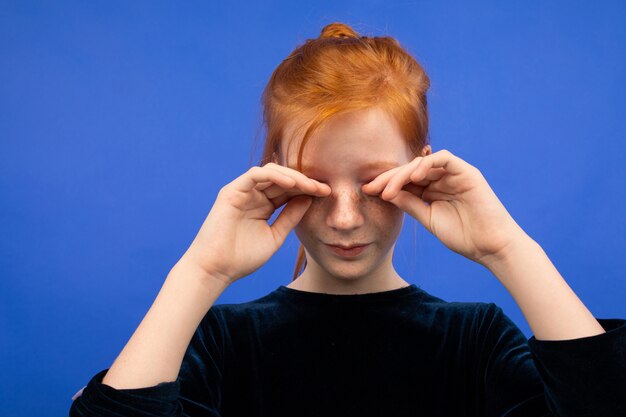 Fille se frotte les yeux en raison de la sécheresse sur le bleu