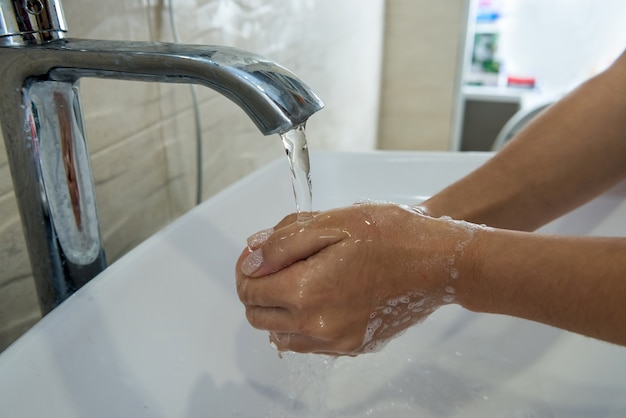 Fille se lavant les mains avec du savon dans la salle de bain pour l'hygiène personnelle et la prévention de la propagation de Covid19.