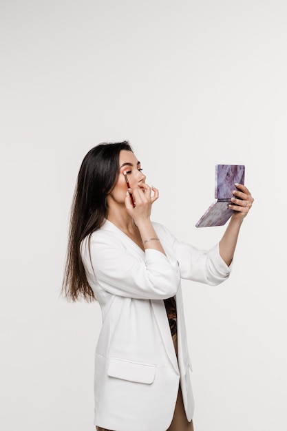 Une fille se maquille avec un pinceau en utilisant une palette de couleurs pour dessiner des ombres sur ses yeux Cosmétiques professionnels pour maquilleuse pour une peau parfaite