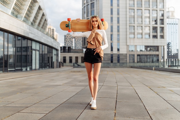 La fille se promène dans la ville sur un longboard. Photo de haute qualité