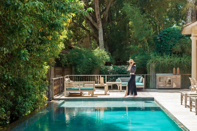 Une fille se promène le long de la piscine privée d'un hôtel de luxe à Bali